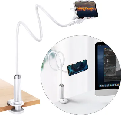 A white flexible gooseneck phone holder with a clamp base is shown attached to a wooden table. A second inset image shows the holder attached to a desk next to a computer monitor.