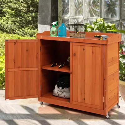 A wooden storage cabinet with doors and shelves, placed outdoors on a patio.