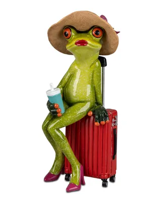 A decorative figurine of a frog dressed as a traveler, sitting on a suitcase and holding a drink.