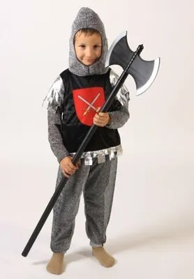 A young boy dressed in a knight costume holding a toy axe.