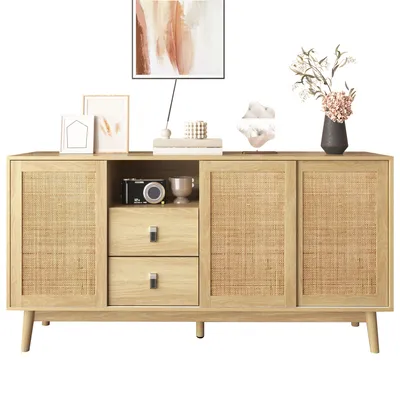 A wooden sideboard with rattan doors and drawers, decorated with framed pictures, a camera, a cup, and a vase with flowers.