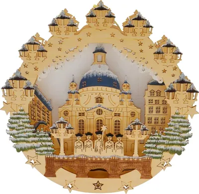 A wooden Christmas ornament depicting the Frauenkirche in Dresden, Germany, with snow-covered trees and figures on a bridge.