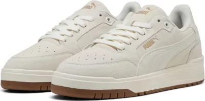 A pair of cream-colored Puma sneakers with brown soles.