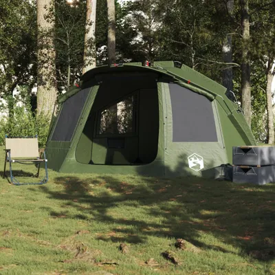 A green tent set up in a wooded area with a camping chair and storage boxes nearby.