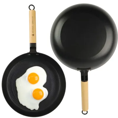Two frying pans, one with two fried eggs, on a white background.