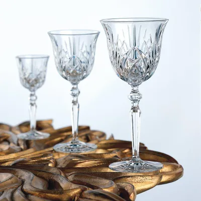 Three crystal wine glasses of varying sizes are arranged on a decorative golden surface.