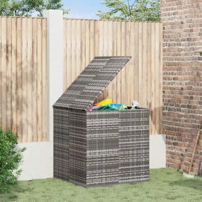 A grey rattan storage box with its lid open, filled with colorful items, sits on a green lawn in front of a wooden fence.