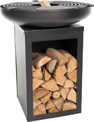 A black metal fire pit with a grill grate on top, sitting on a black metal stand filled with firewood.