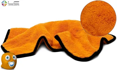 An orange microfiber drying towel with a black edge, shown spread out on a white background. A magnified inset shows the texture of the towel. A small cartoon character is in the lower left corner.