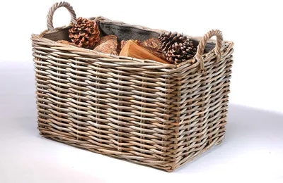 A rectangular wicker basket filled with pine cones and firewood, presented against a white background.