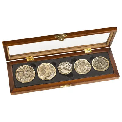 A set of five gold-colored coins with embossed designs, displayed in a wooden box with a glass lid.