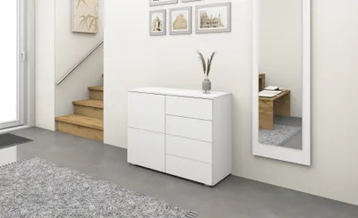 A white dresser is shown in a hallway next to a staircase and a mirror.