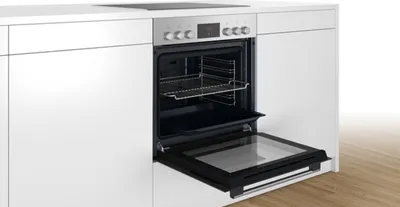 A built-in oven with its door open, showing the interior racks and baking tray.