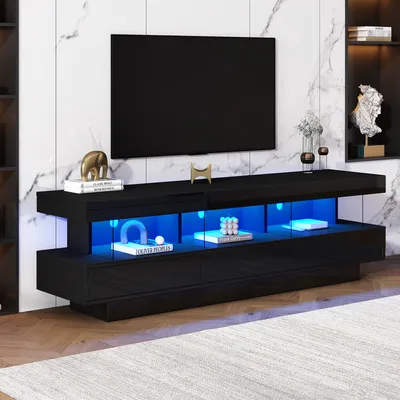 A modern black TV stand with blue LED lighting, displaying decorative items and books, in a living room setting with a marble-patterned wall.