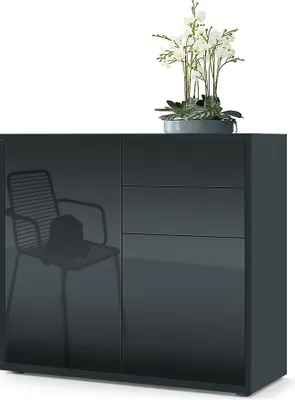 A dark gray sideboard with a reflection of a chair and hat on the left door, and three drawers on the right. A potted plant with white flowers sits on top.
