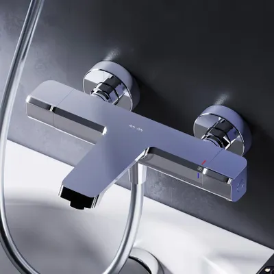 A close-up shot of a modern chrome shower thermostat mounted on a dark gray tiled wall above a white bathtub.