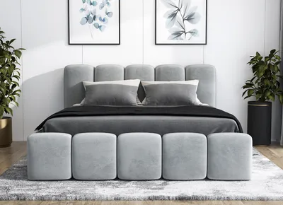 A modern bedroom setting with a gray upholstered bed, pillows, and a bench at the foot of the bed.