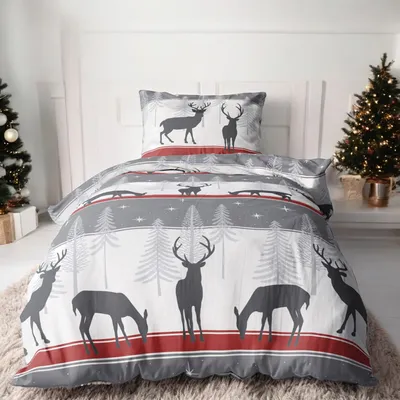 A Christmas-themed duvet cover and pillow set with a deer and forest motif, displayed on a bed with Christmas trees in the background.