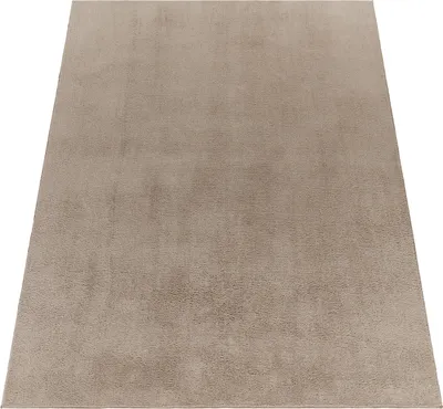 A plain taupe rug is shown from a diagonal angle against a white background.