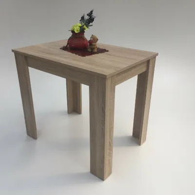 A light oak-colored dining table with decorative items on top, set against a white background.