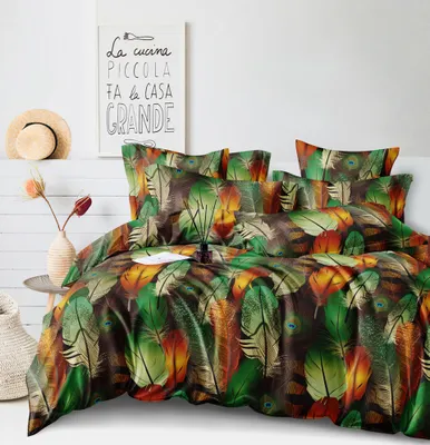 A bed with a colorful feather-patterned duvet cover and pillows, set against a white wall with a framed picture and a straw hat on a shelf.