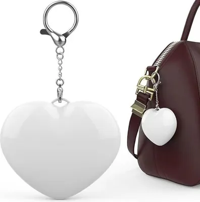 A white heart-shaped keychain is shown on the left, and a similar keychain is attached to a brown handbag on the right.