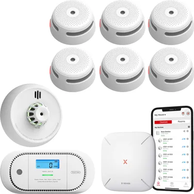A collection of smart home safety devices including smoke detectors, a carbon monoxide detector, a heat detector, and a base station, along with a smartphone displaying a connected app.