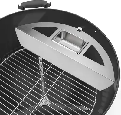 Close-up view of a grill accessory inside a charcoal grill.