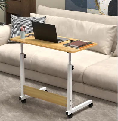 A mobile laptop table with a laptop, books, and pens on it, placed next to a sofa.