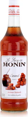 A bottle of Monin Caramel syrup against a white background.