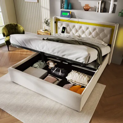 A bed with its storage compartment open, showing various items inside. The bed has a tufted headboard and a yellow accent. There are charging devices on the headboard.