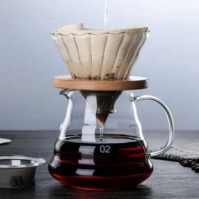 Produktbild von 600 ml und 350 ml V60 Kaffeefilter aus klarem Glas mit hellgrauer Oberfläche und natürlichen Holzhalterungen im minimalistischen japanischen Stil – ein wiederverwendbares Pour-Over-Set für puristischen Kaffeegenuss. Der Edelstahl-Filter passt perfekt zu Hario V60 (2.0 und 3.0) und anderen Markenmaschinen, liefert durch doppelte Filtration (Edelstahlgewebe + lasergeschnittener Filter) volles Aroma und behält natürliche Öle bei. Ideal für 4–6 Tassen oder 8–10 kleine Tassen. Einfache Reinigung unter fließendem