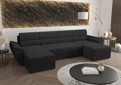 A dark gray U-shaped sectional sofa is shown in a modern living room setting, with a textured wall art and a coffee table in the foreground.