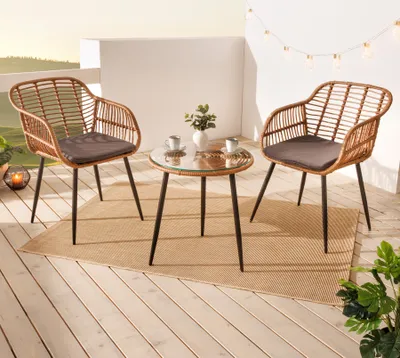 A small bistro set with two chairs and a table on a wooden deck, decorated with string lights.