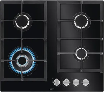 A top-down view of a black gas stovetop with four burners. One burner is lit with blue flames.