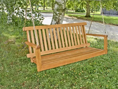 A wooden swing bench is hanging from a tree in a garden setting.