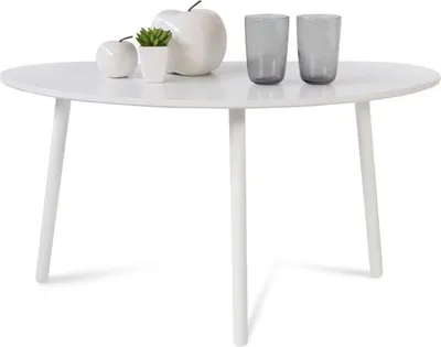 A white oval coffee table with decorative items and glasses on it.
