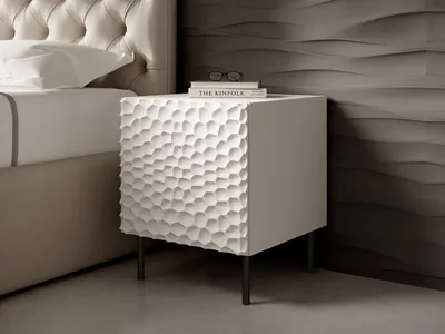 A white textured nightstand next to a bed, with books and glasses on top, in a bedroom setting.