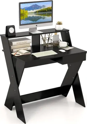 A black computer desk with a monitor, keyboard, mouse, books, and a clock on it.
