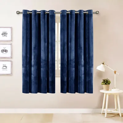 A pair of navy blue velvet curtains hangs on a curtain rod in front of a window. To the left are three framed pictures with simple line drawings. To the right is a small white side table with a white lamp and a potted plant.