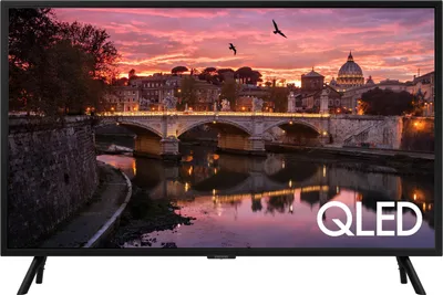 A television displaying a scenic view of a city at sunset, with the 'QLED' logo in the bottom right corner.