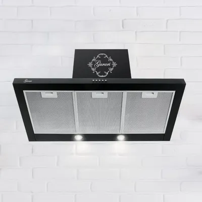 A black kitchen hood mounted against a white brick wall.
