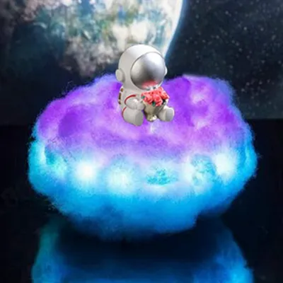 An astronaut figurine sits on a fluffy, illuminated cloud.