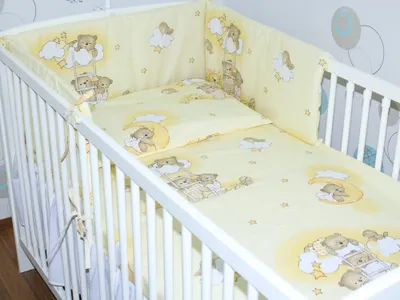 A baby crib with bedding featuring a teddy bear theme.