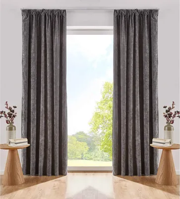 Two dark gray curtains are shown hanging in front of a window with a view of trees and sky. Small wooden side tables with decorative items are placed on either side of the window.