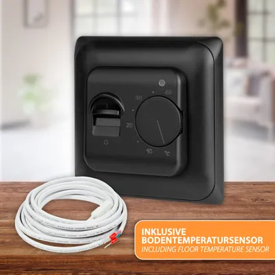 A black thermostat with a temperature dial and a coiled white cable are placed on a wooden surface, with a blurred interior background.