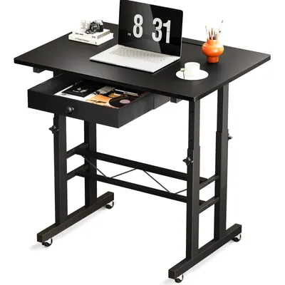 A black adjustable height desk with a laptop, books, and a vase on top, and a drawer pulled out.