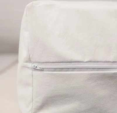A close-up of a white zippered cover on a cushion or mattress.