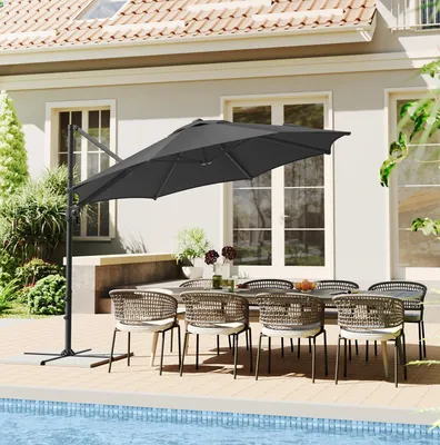 An outdoor patio setting with a table, chairs, and a large cantilever umbrella next to a swimming pool.