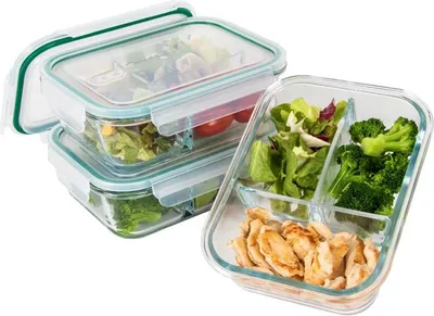 A set of glass food containers with lids, one of which is open and shows food divided into compartments.